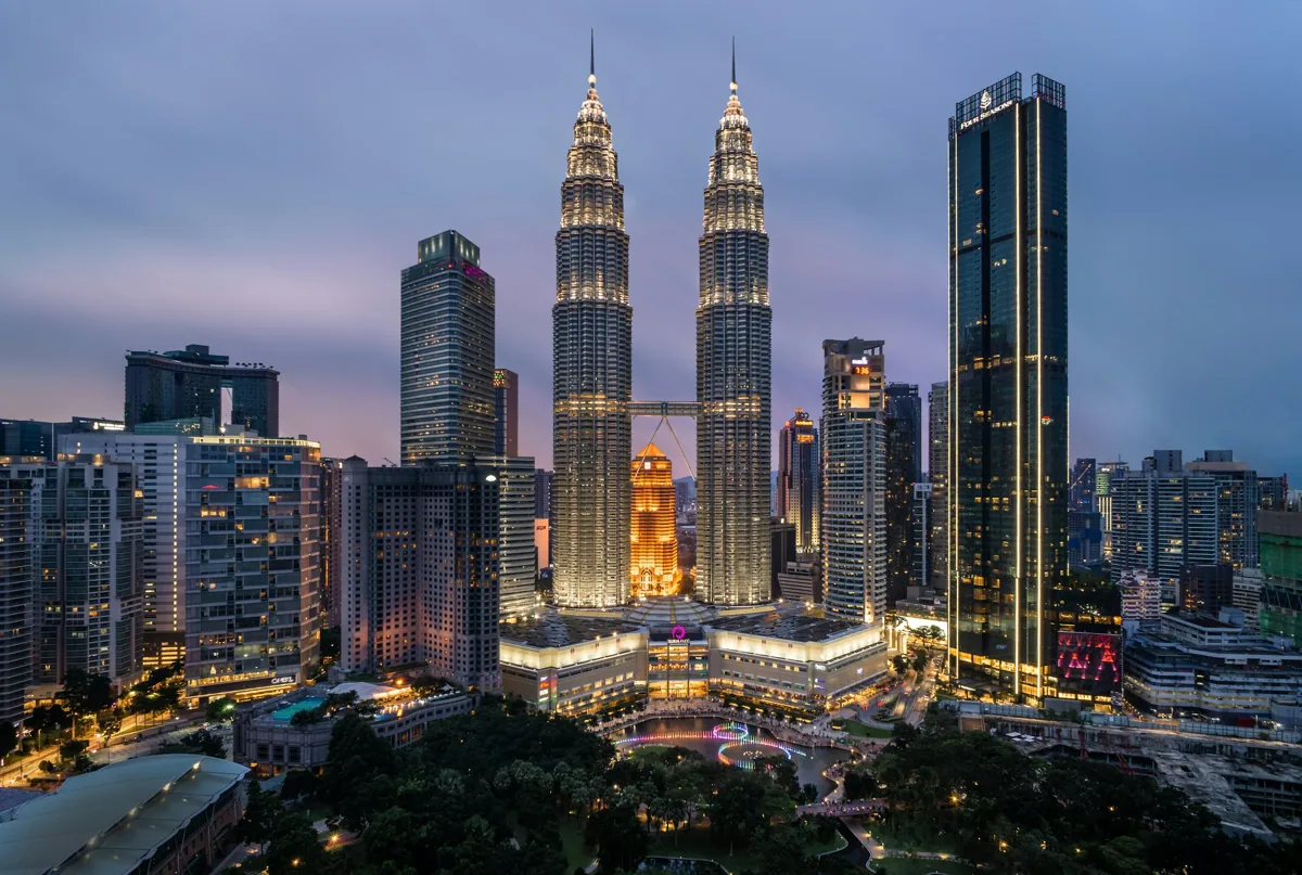 The illuminated Petronas Twin Towers and surrounding Kuala Lumpur skyline at dusk